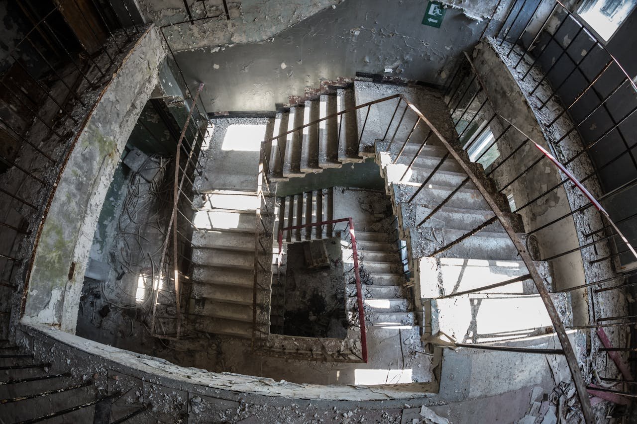 A decaying spiral staircase in an abandoned industrial building, creating an eerie atmosphere.