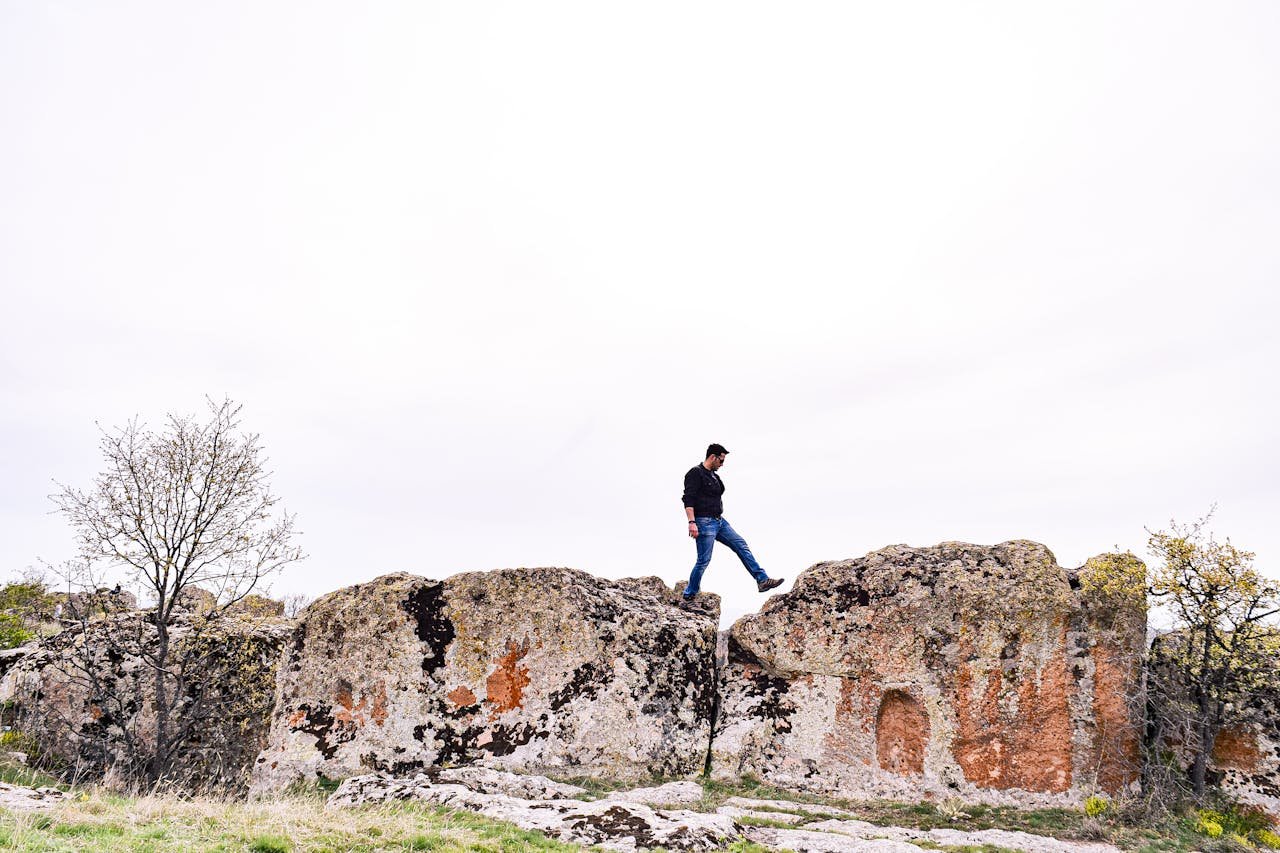A man hiking along rugged rocks in a serene, open landscape, perfect for outdoor adventure themes.